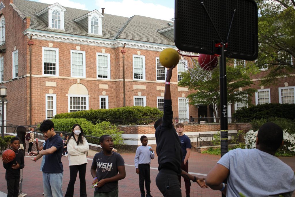 Tutee making a dunk shot playing basketball outside of Levering at the 2023 field day