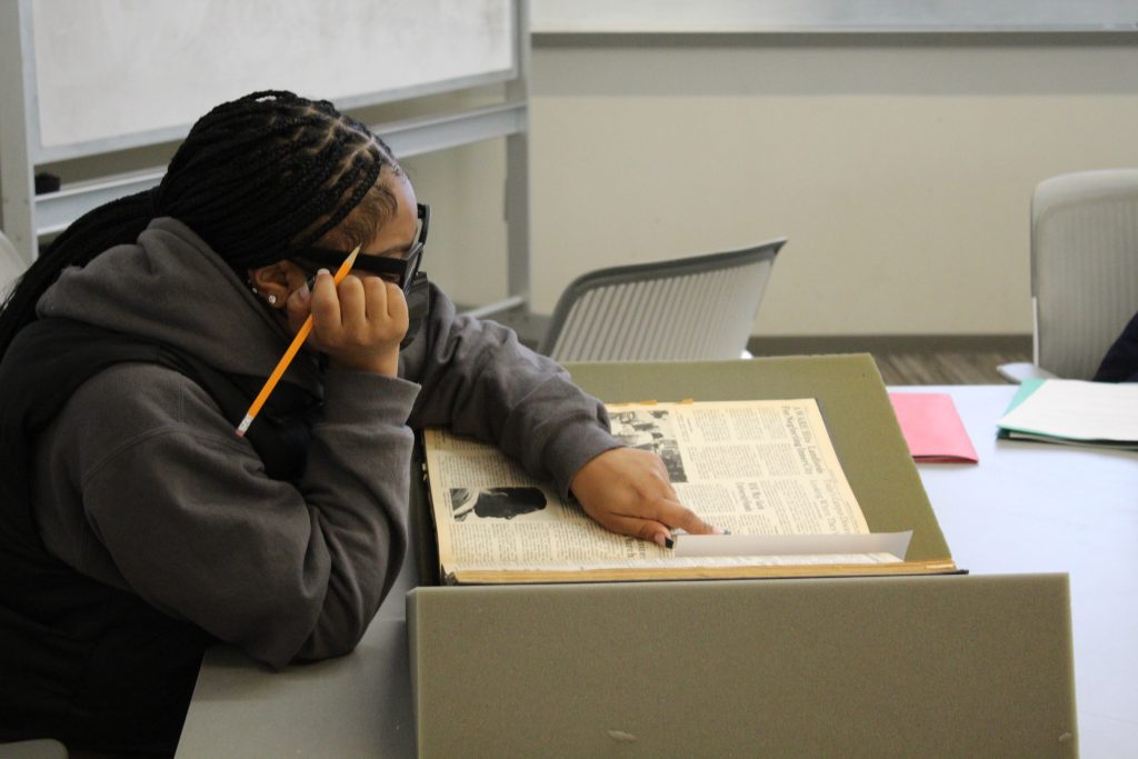 Student looking at old JHU student newsletters